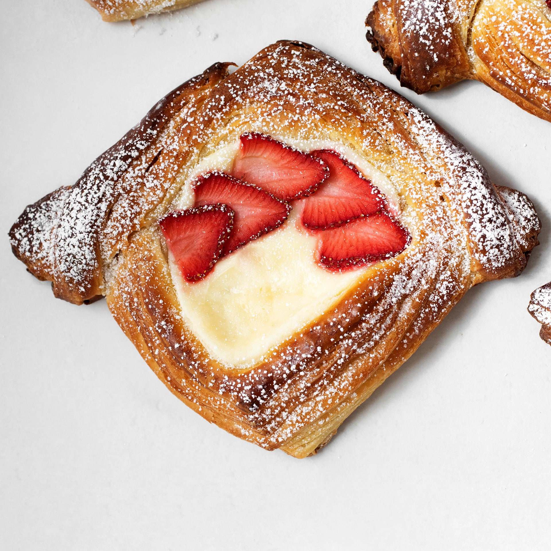 A danish filled with cream and sliced strawberries.